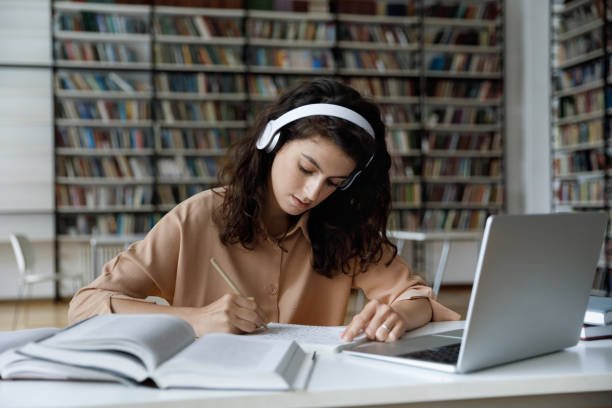 Student writing an essay with a laptop in a library